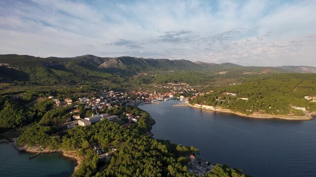Aerial view of Jelsa town and harbor showing the clear waters contrasting with the red roofed buildings surrounded by green trees, Jelsa, Split-Dalmatia County, Croatia.