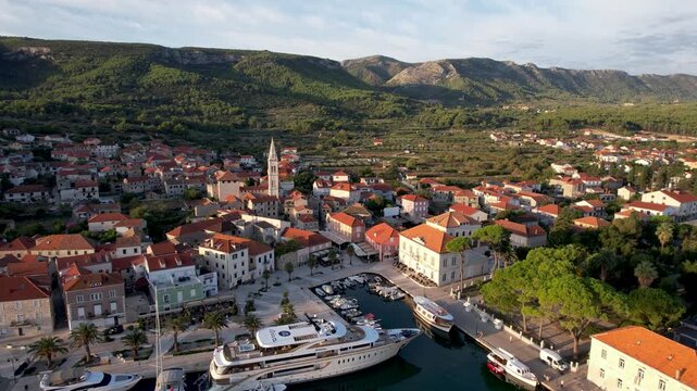 Aerial view of the charming Jelsa harbor, where yachts and boats rest on the clear waters contrasting with the red-tiled roofs, Jelsa, Split-Dalmatia County, Croatia.