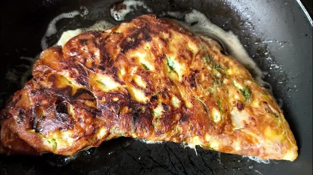 Cooking a fluffy omelet in a metal frying pan on a kitchen stove