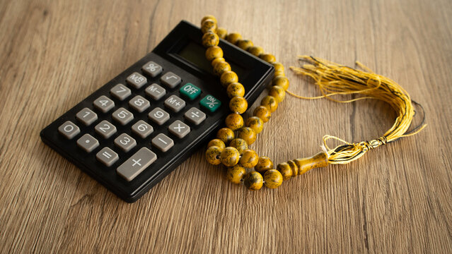 Black calculator with Islamic prayer beads representing religious finance and zakat
