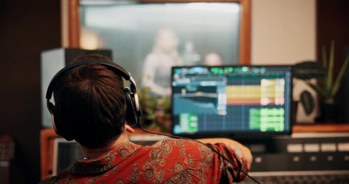 Recording, producer and talking to artist in studio for visual cue, directing performance or music. Back, headphones and man with signal to musician for song composition, audio engineering and timing