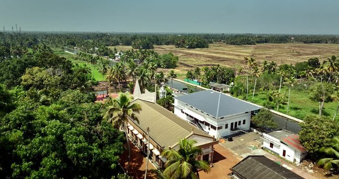 Aerial view of the Alleppey backwaters in Kerala showing traditional boats, narrow canals, palm-lined banks, village houses, and lush green paddy fields, famous tourism destination in South India.
