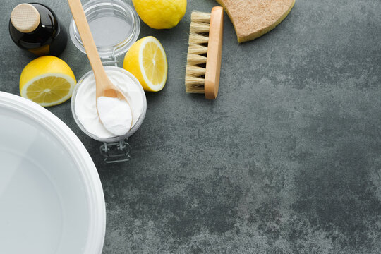 Natural remedies: baking soda, lemon, vinegar, brush, sponge, cold water for removing stains from clothes on a concrete background. Sustainable living and zero waste concept. top view. Space for text