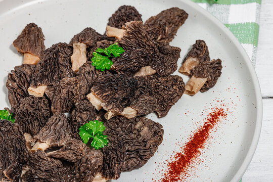 Raw black morel mushrooms with fresh parsley. Vegan ingredient for cooking healthy food