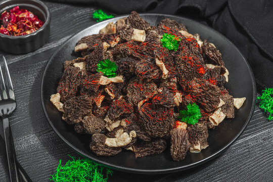 Raw black morel mushrooms with fresh parsley. Vegan ingredient for cooking healthy food