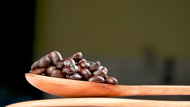 Cinematic eye-level rotating macro of glossy dark roasted coffee beans on a wooden spoon. Premium moody texture with shallow depth of field.
