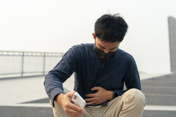 Asian man wearing face mask feeling unwell from air pollution and PM2.5 outdoors. © NINENII