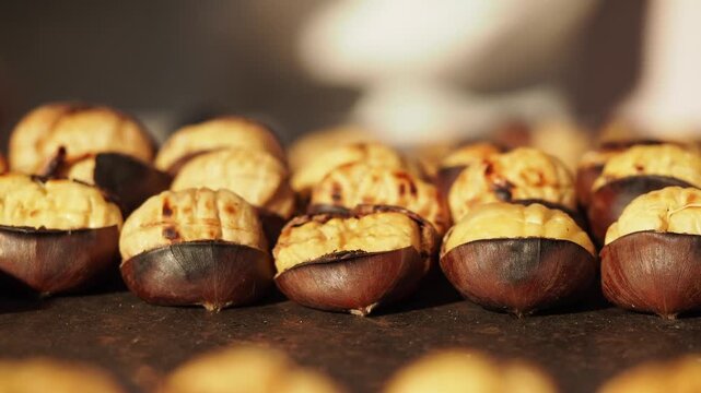 Roasted chestnuts sizzling on hot metal plate close up street food market dynamic clip.