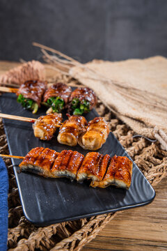 Assorted glazed yakitori skewers on black platter
