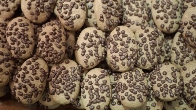 Close up slow zooming out shot of oval chocolate chip cookies arranged in a bakery display.