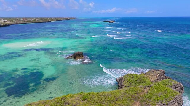 Aerial view of turquoise water, coral reefs, and green rocky cliffs along the Indian Ocean coastline of Watamu Beach, Kenya.
