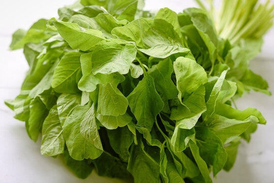 Closeup of fresh spinach leaves bundled together, showing vibrant green color and natural texture.