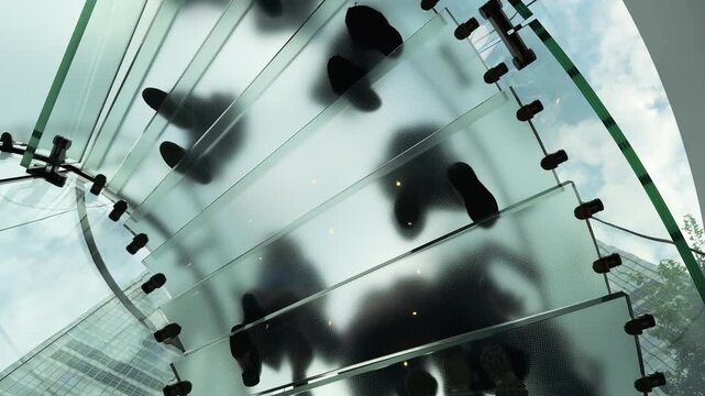 Look up to Glass Staircase above with People feet Silhouettes walking