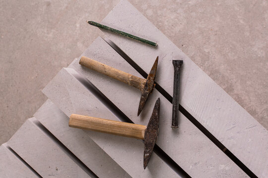 Stone carving hammers and chisels arranged on grey stone slabs flat lay artisan tools