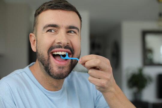 Man cleaning his teeth with plastic pick 