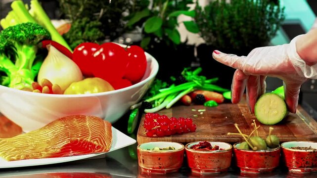 Chef slices avocado beside salmon fillet and fresh vegetables, herbs and berries on kitchen counter for healthy meal prep, gourmet cooking ingredients and seasonings