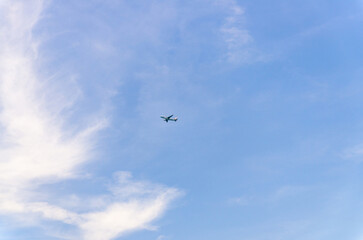 Fototapeta premium Airplane takes off into a blue sky with white clouds, Passenger plane aircraft flying across blue sky background, aircraft gaining altitude, view from below