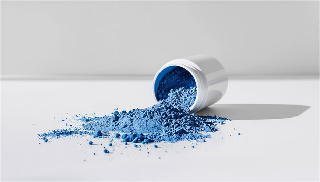 Blue copper peptide powder spilled from cosmetic container on white background, skincare ingredient concept