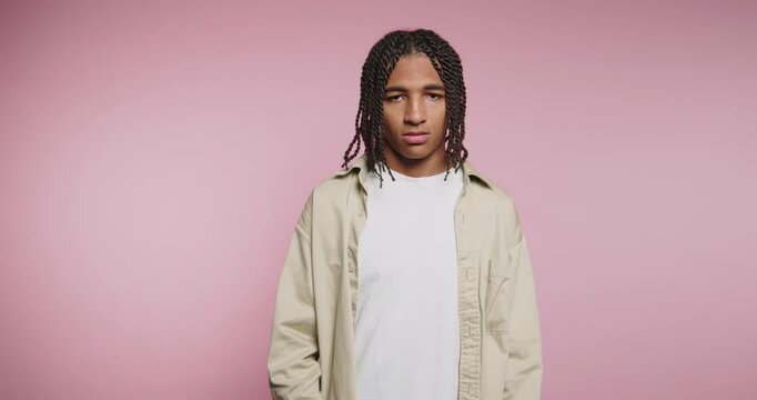 Young man shares thoughts and feelings while standing against a pink background in a studio setting