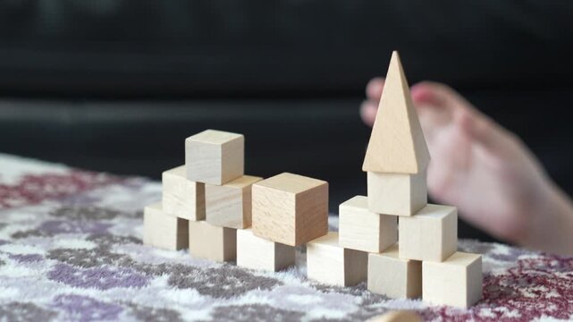 Wooden blocks scatter through the air as children knock down structures capturing playful destruction and learning of cause and effect during active play.