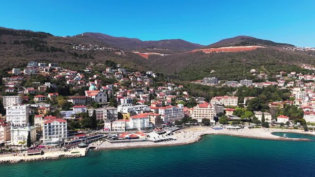aerial panorama of Opatija bay with curved promenade, colorful buildings and mountainous background, showcasing Adriatic coastal urban layout. Opatijska rivjera. Kvarner bay