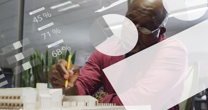 Senior architect pointing yellow pencil at white scale model, bringing charts and reviewing design