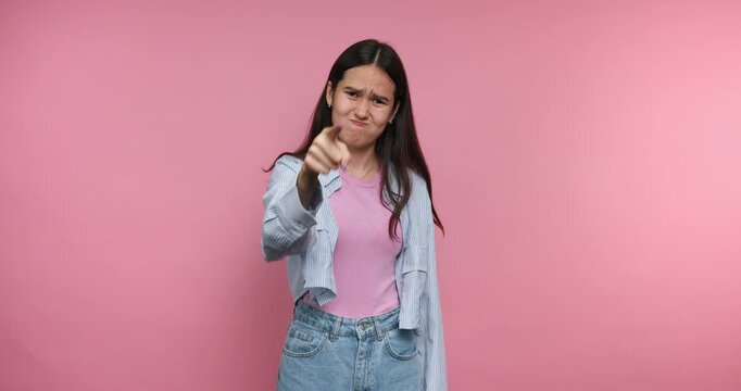 Young woman shows different gestures and expressions against a pink background while standing indoors