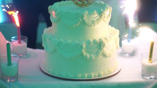 Elegant wedding cake with rings and white flowers, held by newlyweds in celebration