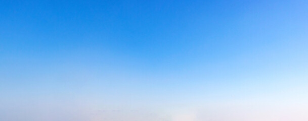 Obraz premium Clear gradient blue sky with subtle haze near horizon, minimal background pattern for design, presentation and wallpaper use.