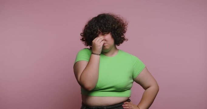 Woman expresses different emotions while in a green shirt against a pink background