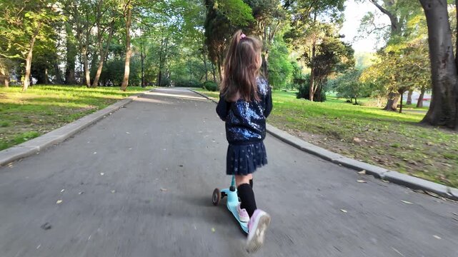Cute little girl riding a scooter in the park