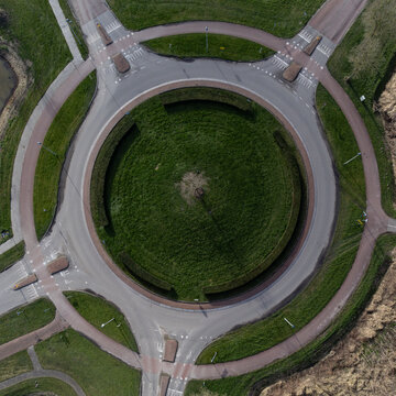 Aerial view of a roundabout, a green oasis encircled by gray roads and red brick paths, Overgooi, Flevoland, Netherlands.