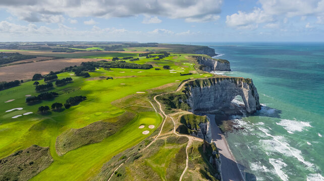 Aerial view of dramatic white cliffs meet the turquoise sea, framing the iconic arch of Etretat, Normandy, France.