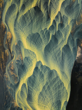 Aerial view of intricate patterns and textures where icy blue rivers meet the golden sands of the Icelandic landscape, Iceland, Iceland.