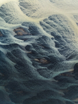Aerial view of glacial rivers intertwine like delicate brushstrokes across the stark landscape, a symphony of icy blues and earthy browns, Iceland, Iceland.