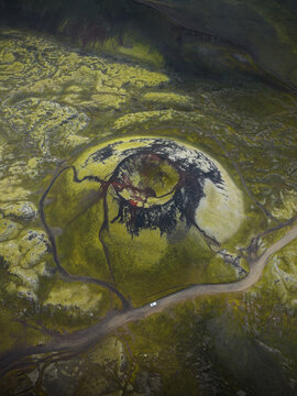 Aerial view of a striking volcanic crater adorned with vibrant green moss, contrasting sharply with the dark interior, Highlands, Iceland.