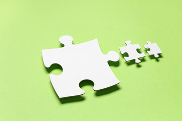 Fototapeta premium Pieces of white jigsaw puzzle on green background