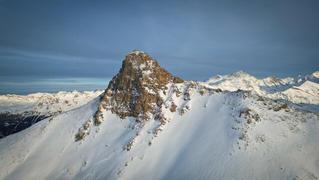 Aerial view of the majestic Becs des Bossons Peak, where sunlight kisses the snow-dusted summits, creating a symphony of light and shadow, Anniviers, Valais, Switzerland.