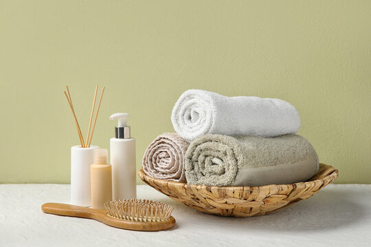 Clean towels, cosmetic products, hair brush and reed diffuser on light table