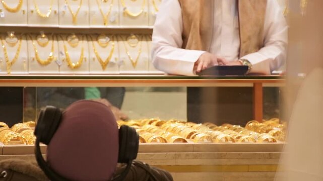 Dubai, UAE - 15th january, 2026:Close-up of gold bracelets in a display case at the Dubai Gold Souq. Seller calculate price and profit in gold luxury jewelery shop