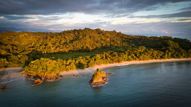 Aerial view of the sun-kissed shoreline where the verdant jungle meets the vast ocean, creating a harmonious blend of colors and textures, Uvita, Puntarenas, Costa Rica.