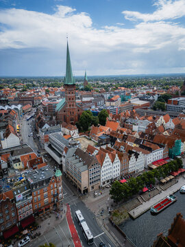 Aerial view of the iconic spire of St. Marien church rises above the terracotta rooftops, blending with the Elbe river's shimmering waters, Lubeck, Schleswig-Holstein, Germany.