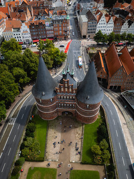 Aerial view of the iconic Holsten Gate standing proudly against the urban tapestry of Lubeck, framed by roads and pathways, Schleswig-Holstein, Germany.