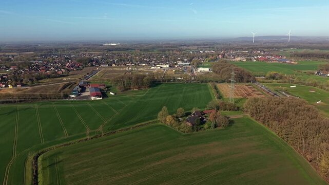 Rural farmland fields and small American town during sunny day and blue sky in spring season. Aerial establishing shot. Peaceful and quiet suburb area in different colors. Countryside city in USA .