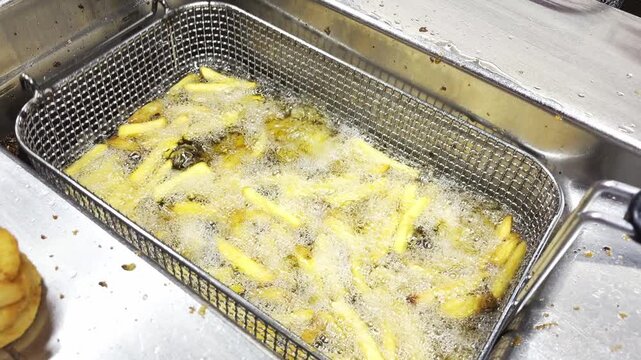 Golden Fried Chips Cooking In Hot Oil. Closeup View Of Freshly Prepared Fried Potato Strips Draining