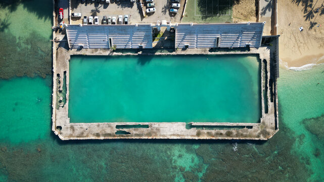 Aerial view of the stark concrete rectangle contrasts with the vibrant turquoise pool and the natural blues of the surrounding ocean, Waikiki, Honolulu, Hawaii, United States.