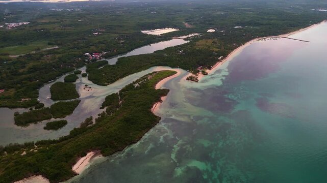 Dramatic drone capture of the Bantayan Island coastline in the Philippines. The camera reveals the intricate patterns of the shallow water and the dark silhouettes of the land