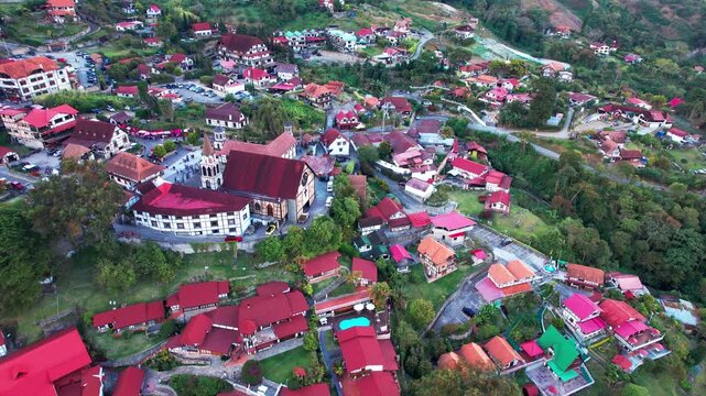 Scenic drone shot of the historic Saint Martin of Tours church and red-roofed houses at dusk in the Venezuelan cloud forest.
