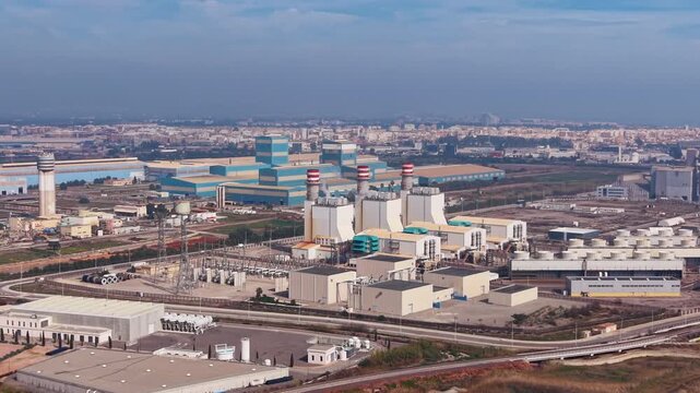 Modern combined cycle gas turbine power plant with exhaust stacks, heat recovery units, and electrical substation in an urban industrial zone