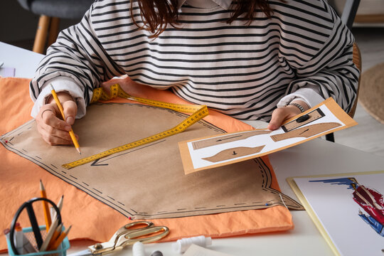 Female fashion designer making pattern at table in studio